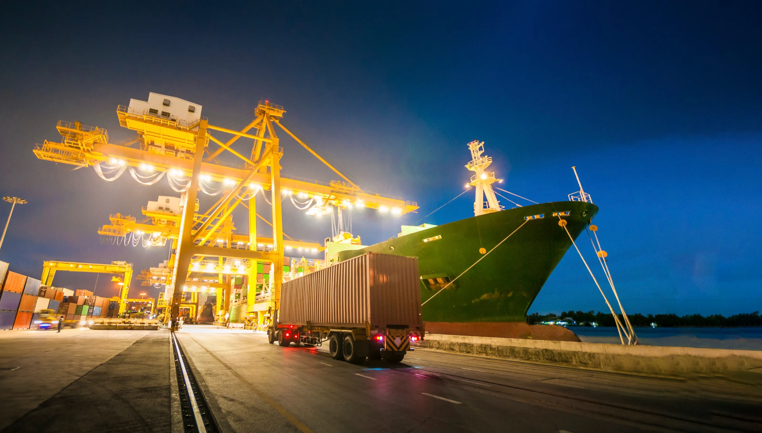 Cargo ship and port cranes illuminated at night