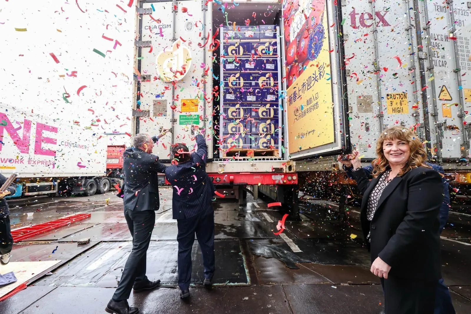 Team celebrating an a1 Apples launch with confetti in front of branded shipping containers
